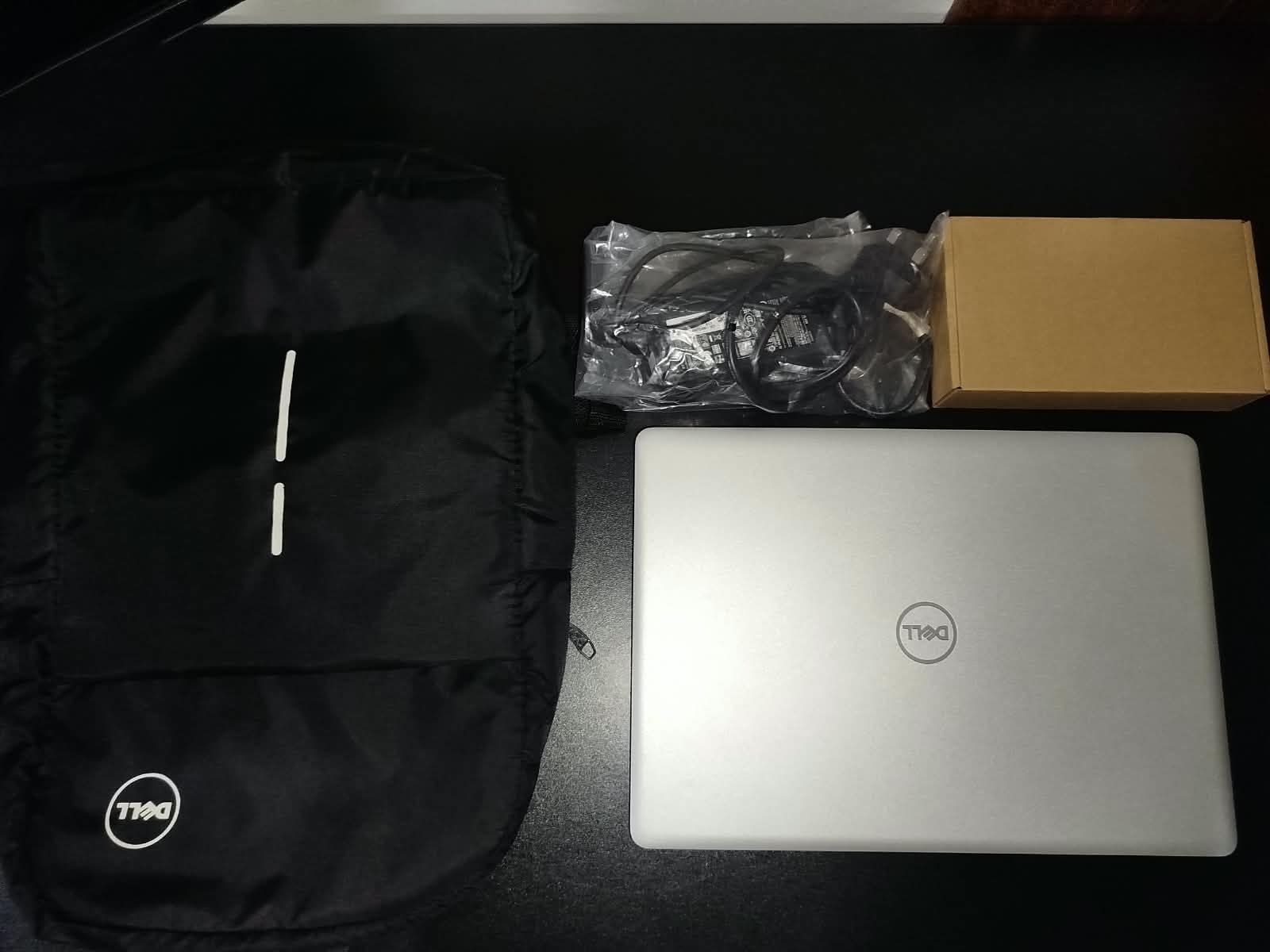 A laptop with its sleeve, charger and box, prepared for handover to a student