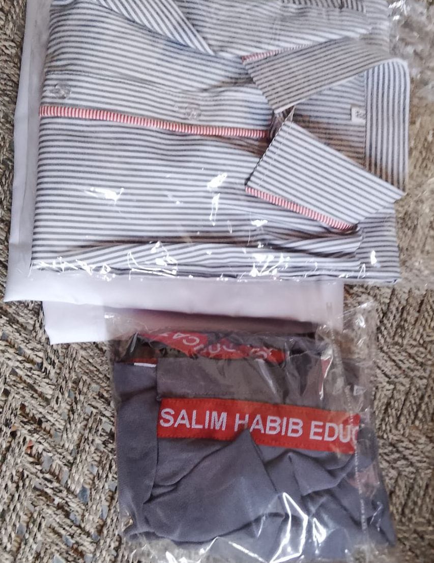 A packed and labelled school uniform — shirt, trousers and tie — ready for handover